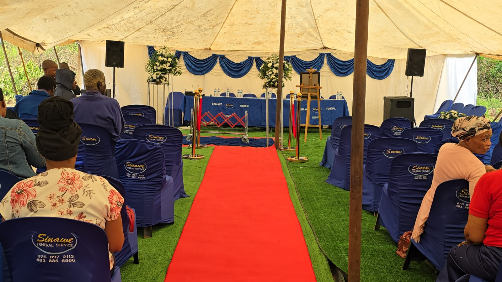 Sinawee Funeral Service tent with blue chair covers and red carpet